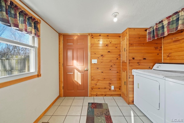 laundry room with wooden walls, baseboards, laundry area, light tile patterned flooring, and washer and dryer