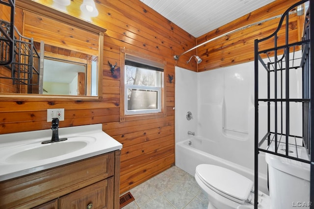 bathroom featuring tile patterned floors, toilet, shower / bathing tub combination, wooden walls, and vanity