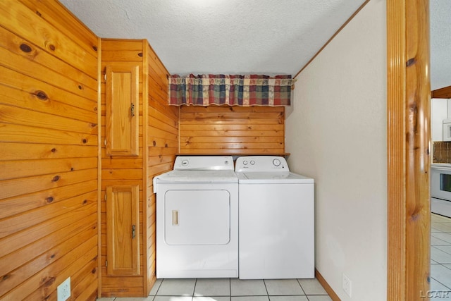 laundry area with a textured ceiling, light tile patterned flooring, and washing machine and clothes dryer