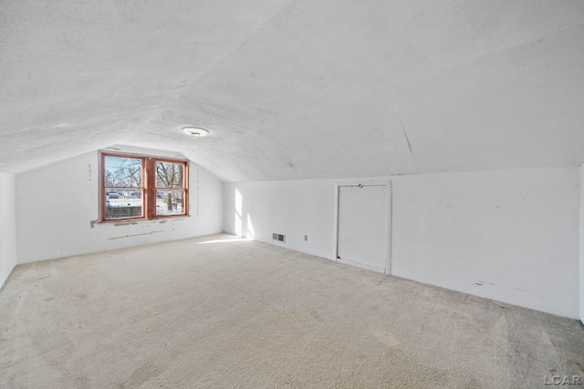 bonus room featuring carpet flooring, a textured ceiling, visible vents, and vaulted ceiling