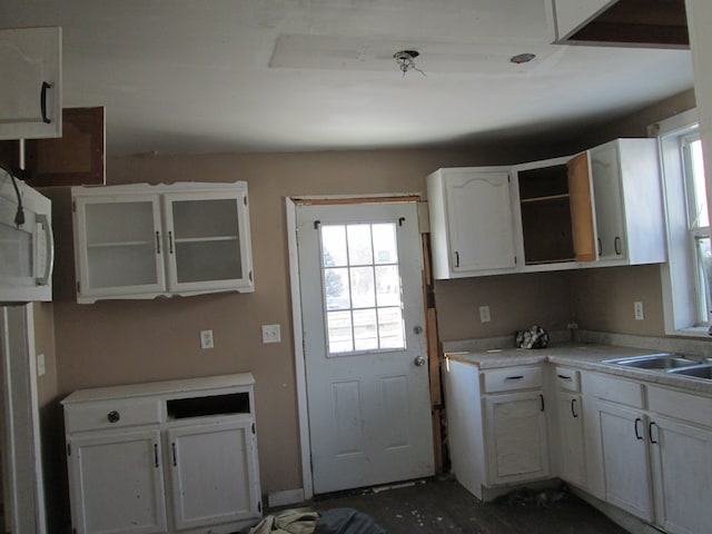 kitchen with a sink, open shelves, light countertops, and white cabinetry