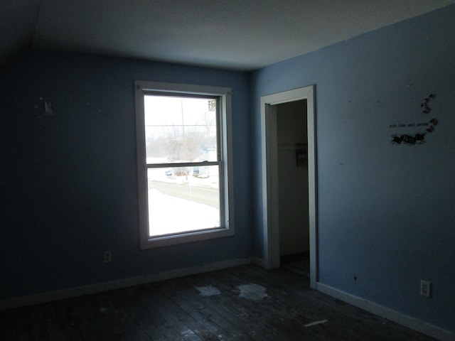 spare room featuring baseboards and wood-type flooring