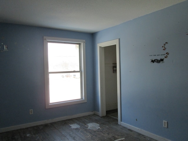 spare room with baseboards and hardwood / wood-style floors