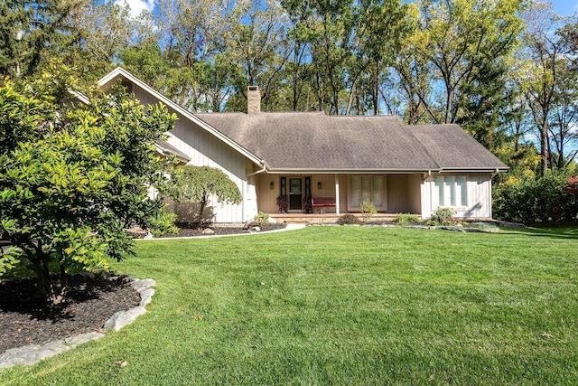 ranch-style home with covered porch, a chimney, a front lawn, and roof with shingles