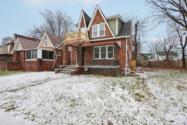 tudor house featuring a balcony and brick siding