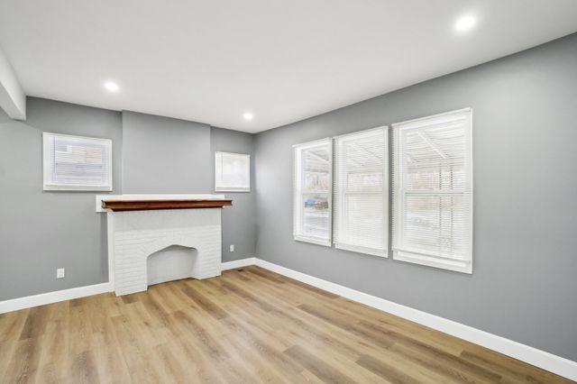 unfurnished living room featuring a brick fireplace, recessed lighting, wood finished floors, and baseboards