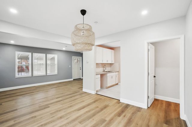 kitchen with light wood-style flooring, white cabinetry, baseboards, and a sink