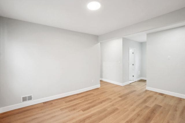 spare room featuring visible vents, baseboards, and light wood finished floors