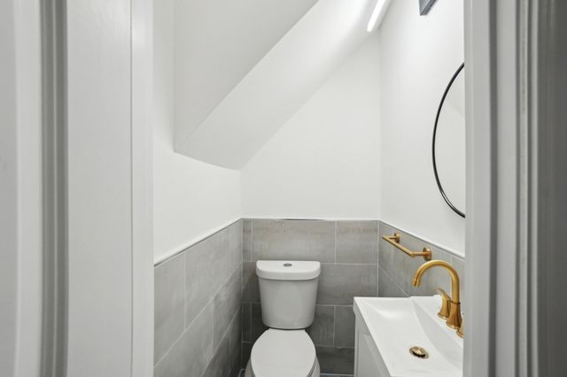 bathroom featuring wainscoting, toilet, and vanity