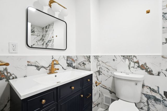 bathroom with visible vents, toilet, a wainscoted wall, and vanity