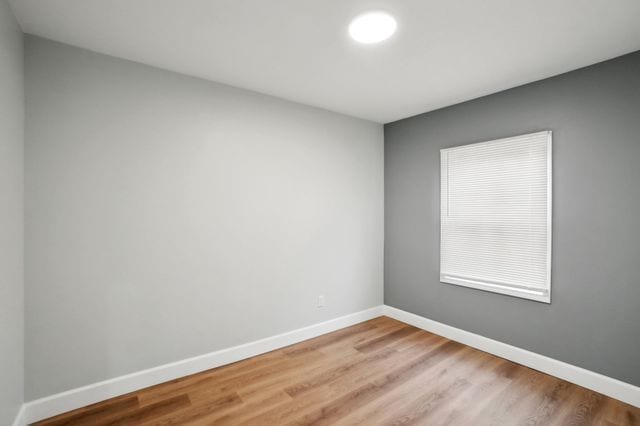 unfurnished room with wood finished floors and baseboards