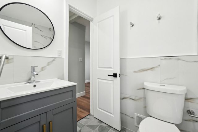 bathroom featuring vanity, tile walls, toilet, and visible vents