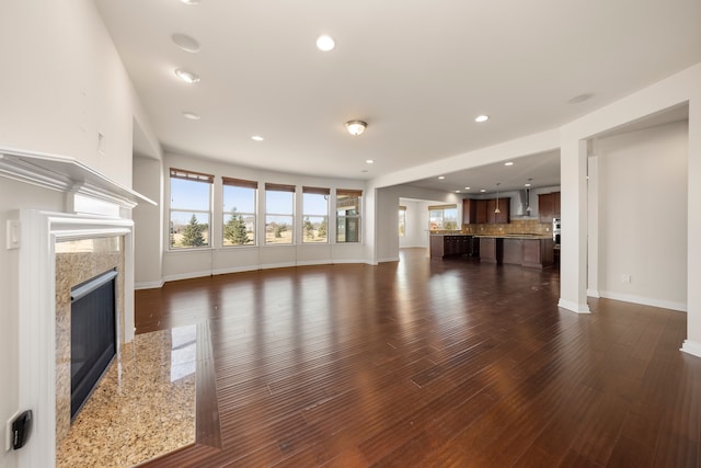 unfurnished living room with recessed lighting, dark wood-type flooring, baseboards, and a premium fireplace