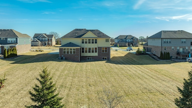 back of house with a residential view, a lawn, and brick siding