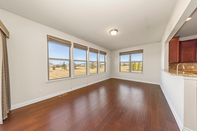 unfurnished living room with dark wood finished floors, visible vents, and baseboards