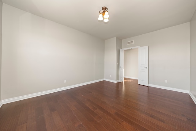 unfurnished room with visible vents, baseboards, and dark wood-style flooring