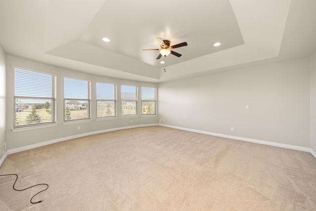 empty room featuring recessed lighting, a raised ceiling, and baseboards