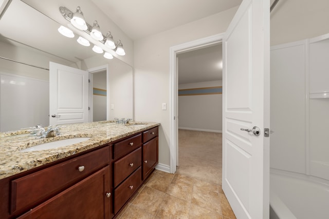 full bath featuring double vanity, baseboards, and a sink