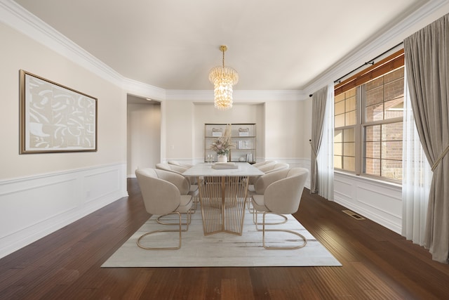 dining room with visible vents, a chandelier, ornamental molding, wainscoting, and dark wood-style flooring