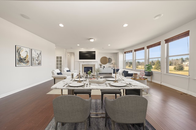 dining room with recessed lighting, baseboards, dark wood-type flooring, and a fireplace