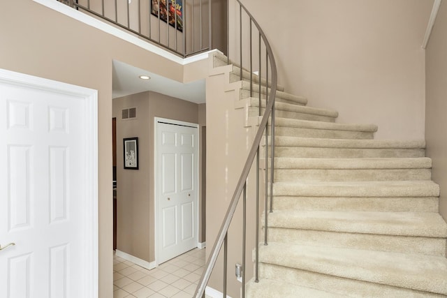 staircase featuring tile patterned floors, visible vents, and baseboards