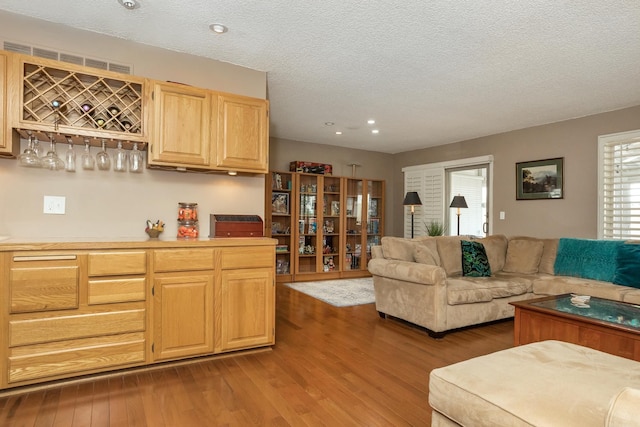 living area featuring recessed lighting, a textured ceiling, a dry bar, and wood finished floors