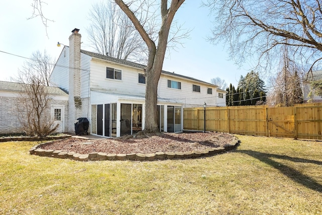 back of property with a lawn, a sunroom, a chimney, and fence