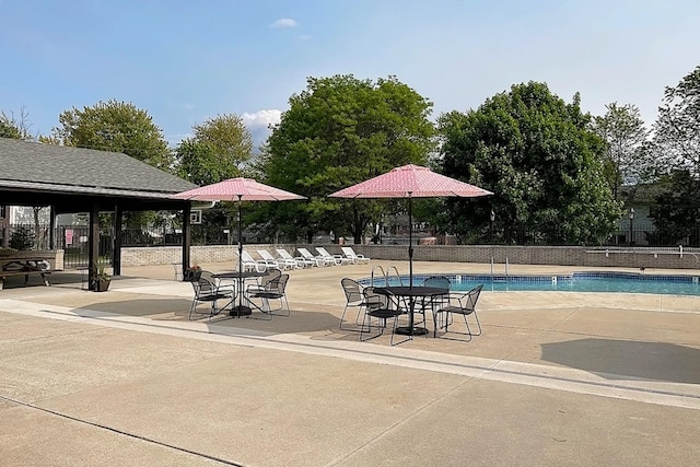 community pool with a patio and fence