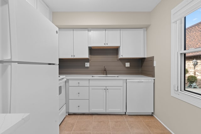 kitchen featuring white appliances, white cabinets, plenty of natural light, and a sink