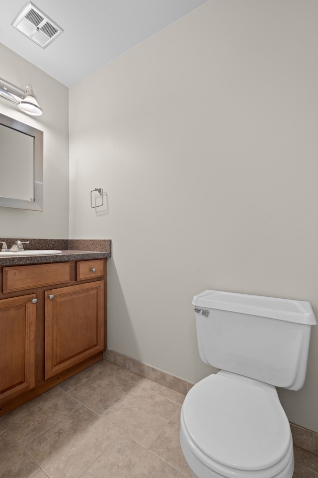 bathroom featuring vanity, baseboards, visible vents, tile patterned floors, and toilet