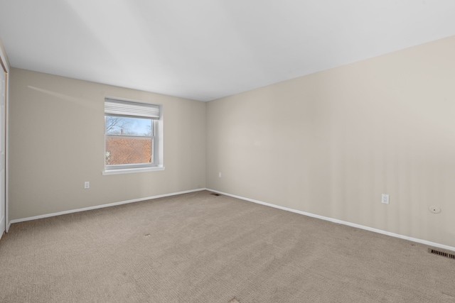 unfurnished room with carpet, visible vents, and baseboards