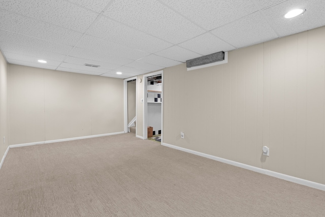 finished below grade area with visible vents, a paneled ceiling, baseboards, and carpet floors