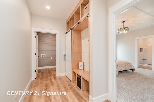 mudroom with baseboards, light wood finished floors, recessed lighting, a barn door, and light colored carpet