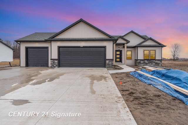 view of front of home with stone siding, driveway, an attached garage, and a shingled roof