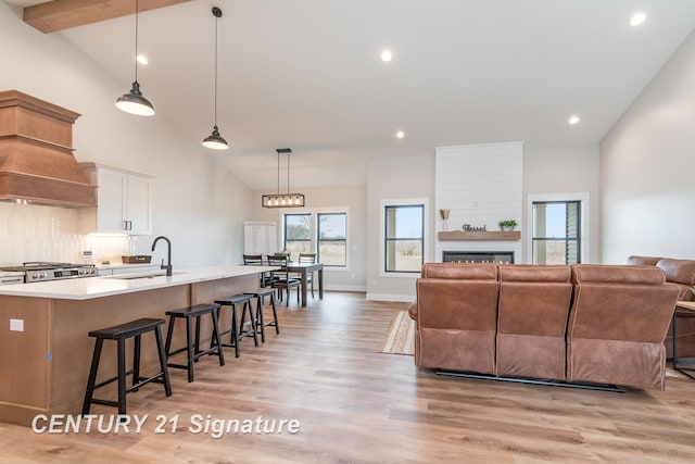 living area featuring light wood-type flooring, high vaulted ceiling, a warm lit fireplace, recessed lighting, and baseboards