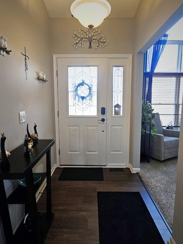 foyer entrance with visible vents, baseboards, and dark wood-style flooring