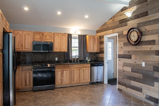 kitchen featuring light brown cabinetry, a sink, lofted ceiling with beams, wooden walls, and appliances with stainless steel finishes