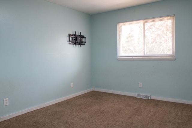 carpeted spare room featuring visible vents and baseboards