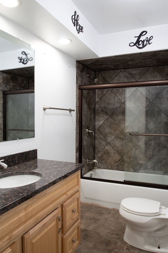 bathroom featuring tile patterned flooring, toilet, vanity, and shower / bath combination with glass door