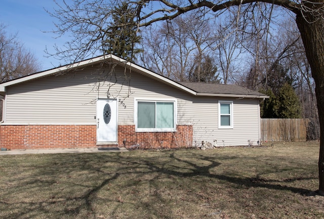 ranch-style home featuring brick siding, a front lawn, and fence