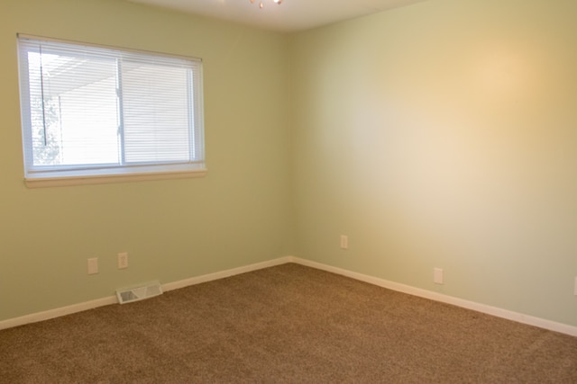 unfurnished room with visible vents, baseboards, ceiling fan, and dark carpet