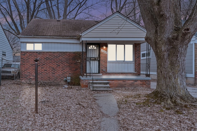 view of front of property with brick siding and a shingled roof