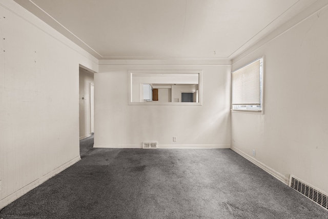 empty room with carpet, visible vents, and baseboards