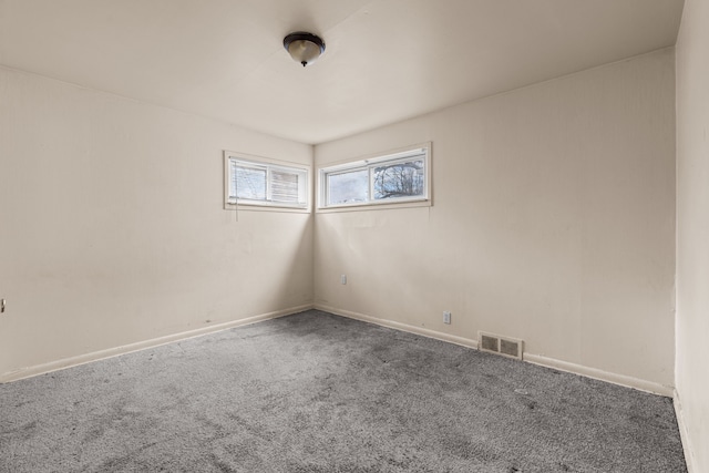 carpeted spare room with visible vents and baseboards