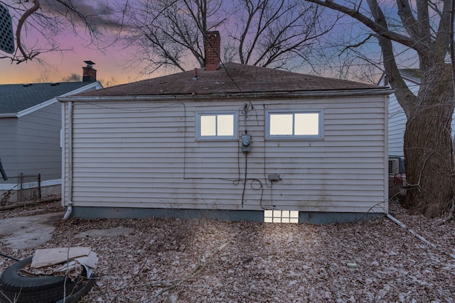 back of house with a shingled roof and fence