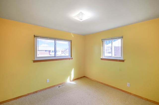 spare room featuring light carpet, visible vents, and baseboards