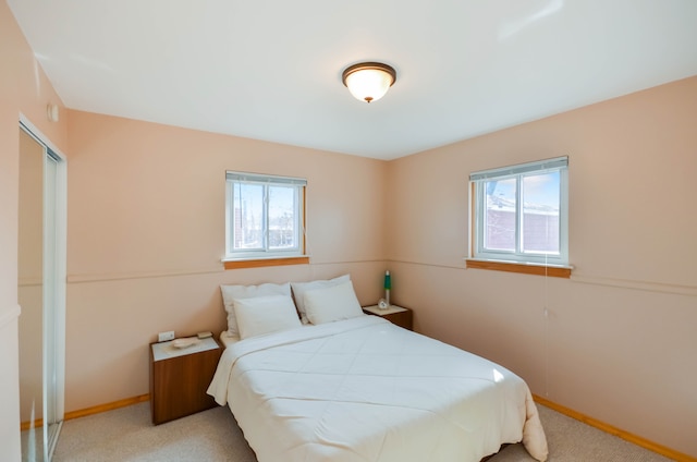 carpeted bedroom featuring a closet, multiple windows, and baseboards