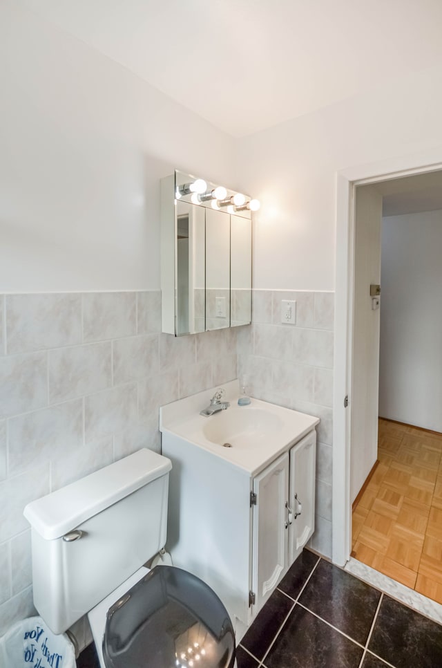 bathroom featuring vanity, a wainscoted wall, tile walls, toilet, and tile patterned floors