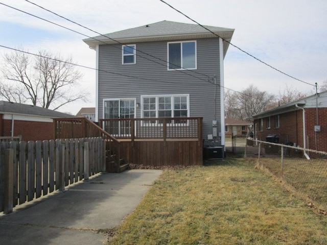 back of property featuring a wooden deck, a lawn, and fence