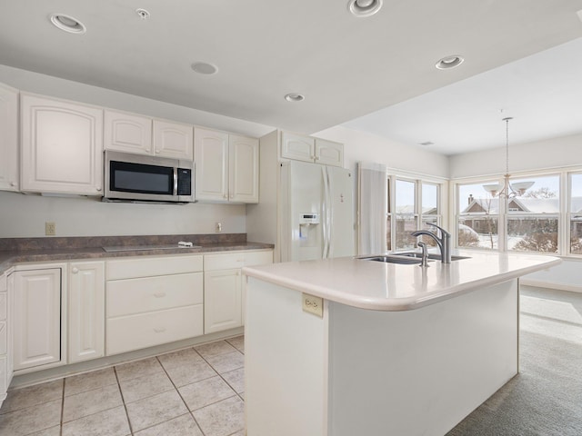 kitchen featuring stainless steel microwave, a wealth of natural light, white fridge with ice dispenser, and a sink